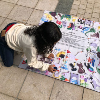 Démonstration avec enfant sur le jeu de l'oie géant nomade en tissu pour jouer en extérieur. Lavable en machine à 30° Idéal ludothèque, crèche, cours d'école. Imaginé par Anne Da Cunha-Guillegault en exclusivité pour la marque An'imato