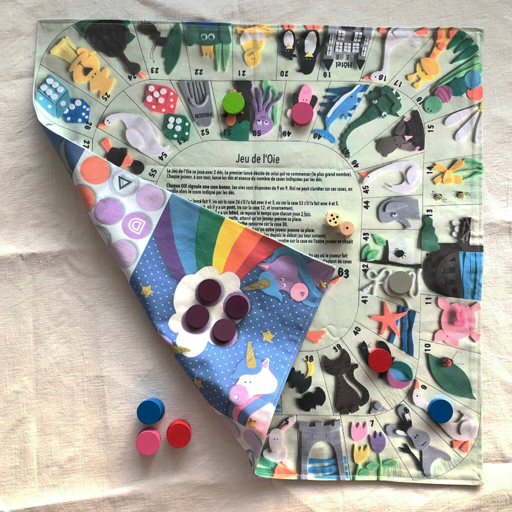 Tapis du double jeux oie et ludo en tissu créé par Anne Da Cunha-Guillegault pour la marque An'imato avec les pions en bois