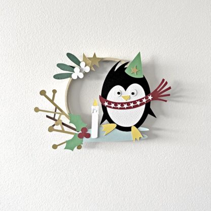 Cercle décoratif spécial Noël avec un pingouin sur la glace et du feuillage d'hiver en papiers découpés Design Anne Da Cunha-Guillegault pour An'imato