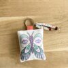 porte-clés colorié du kit pour fabriquer son cadeau Merci maîtresse merci maître ou ATSEM avec un porte-clés papillon en tissu à colorier, des stylos gel et des perles lettre alphabet imaginé par Anne Da Cunha-Guillegault en exclusivité pour la marque An'imato