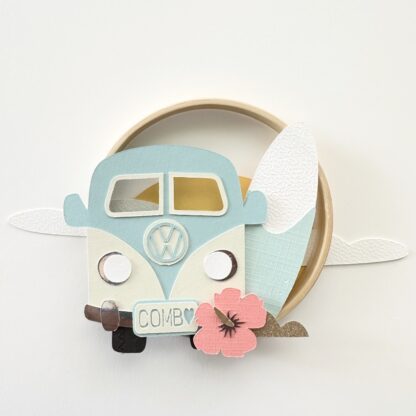 cercle décoratif avec une combi une planche de surf, une fleur hibiscus devant un couché de soleil nuageux réalisé en papiers découpés Design Anne Da Cunha Guillegault en exclusivité pour la marque An'imato