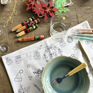 Table de Noël avec la couronne avec des poinsettias en papier du kit imaginé par Anne Da Cunha Guillegault en exclusivité pour la marque An'imato ainsi que le set de table en tissu à colorier de Noël et des feutres à l'eau